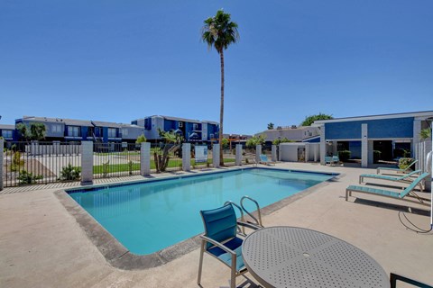 A pool area with a table and chairs and a palm tree.