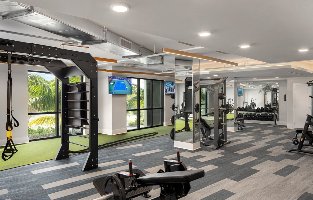 Pet-Friendly Apartments in Boca Raton, FL – CERU - a gym with weights and exercise equipment and a television on the wall