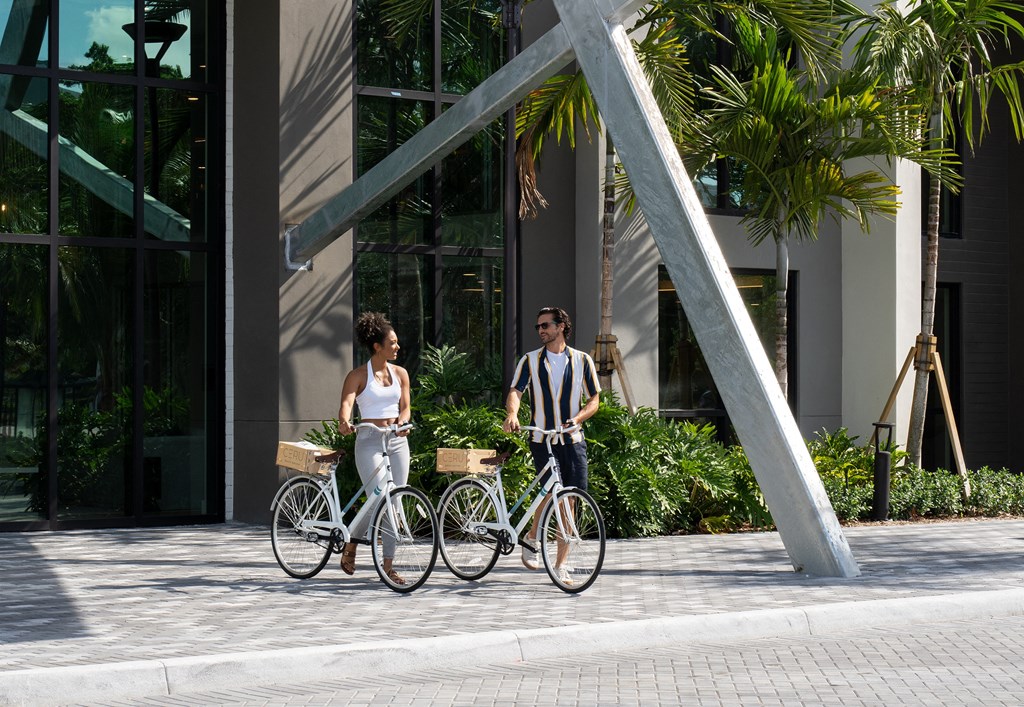 Luxury Boca Raton Apartments – CERU - a man and a woman walking their bikes down the street infront of our community building