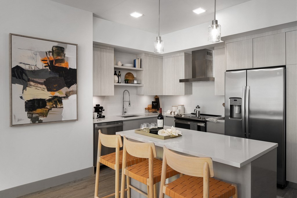 Boca Raton Apartments - CERU -  a kitchen with stainless steel appliances and a white island with four chairs