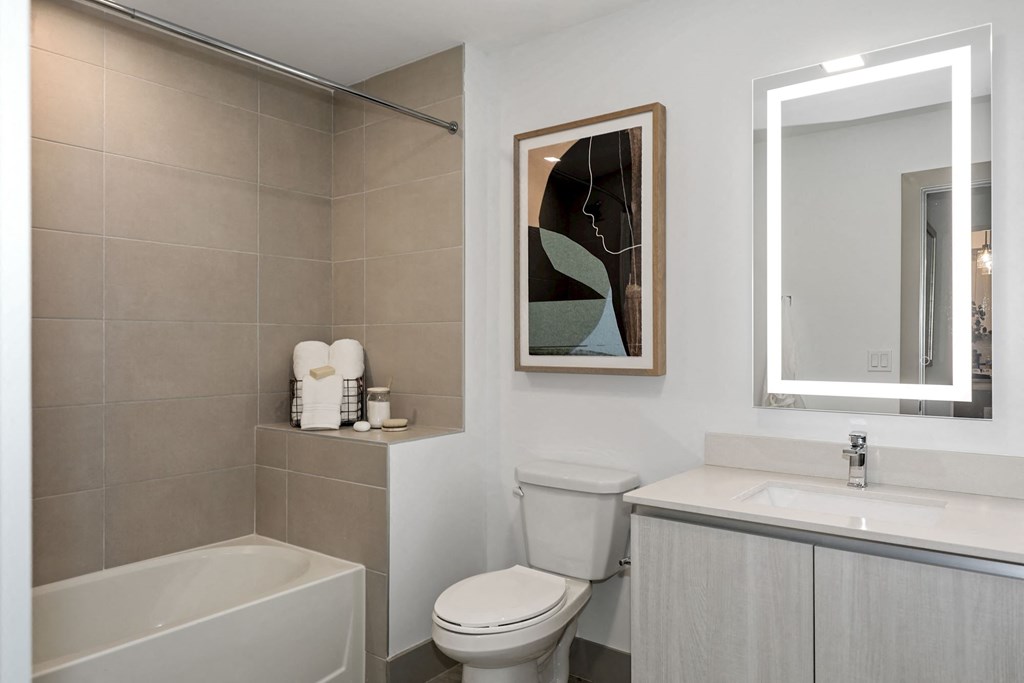 Boca Raton Apartments - CERU - a bathroom with a toilet sink and tub and a mirror