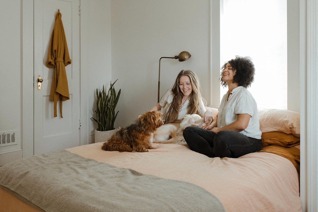 two women sitting on a bed with a dog