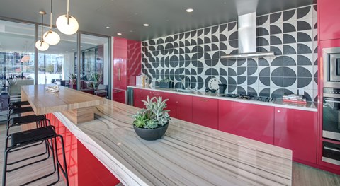 A modern kitchen with a wooden counter and red accents.