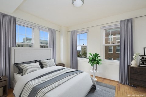 A bedroom with a large bed and a window with a view of a building outside.