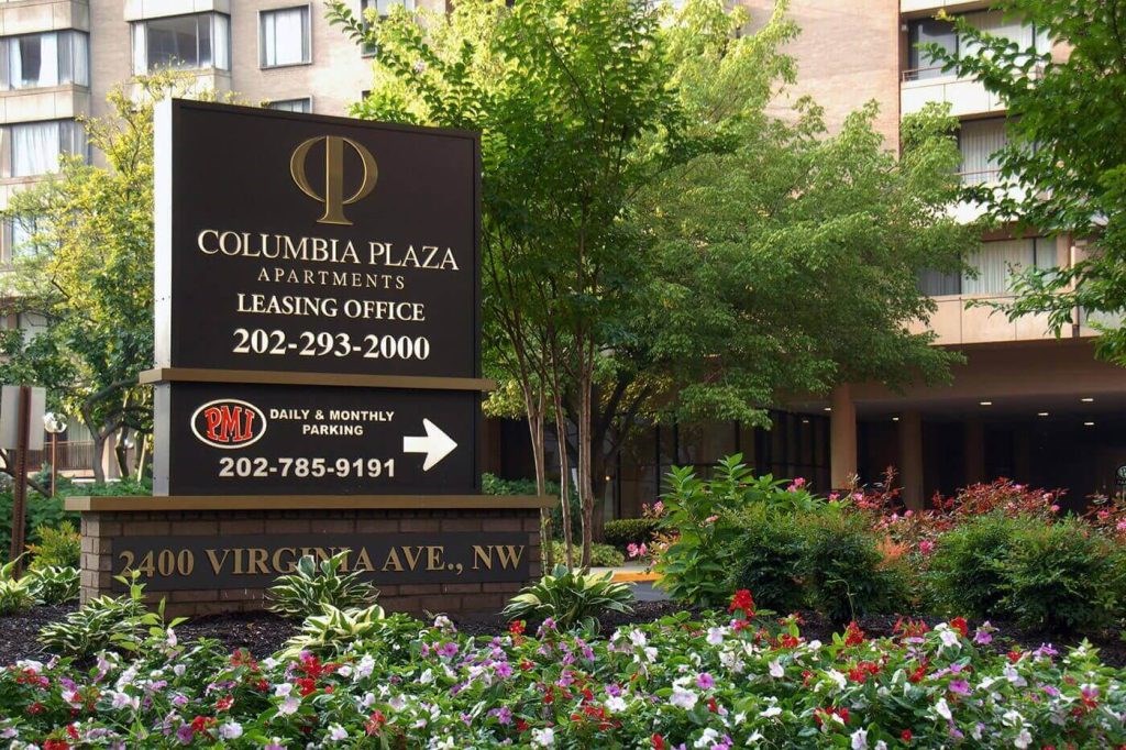 A sign for Columbia Plaza Apartments with a phone number and parking information.