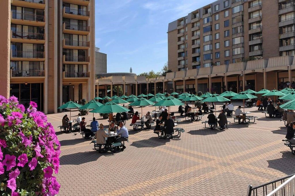 People are sitting under green umbrellas in a courtyard.