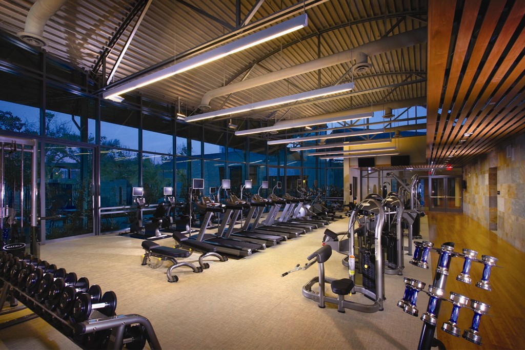 A gym with a variety of equipment including treadmills, weights, and exercise machines.