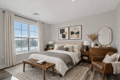 Staged apartment bedroom with large window and modern furnishings at Creekline at Fairfield in Fairfield, Connecticut.