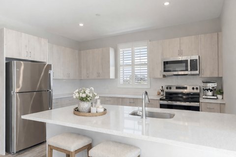 A modern kitchen with a stainless steel refrigerator and a white countertop.