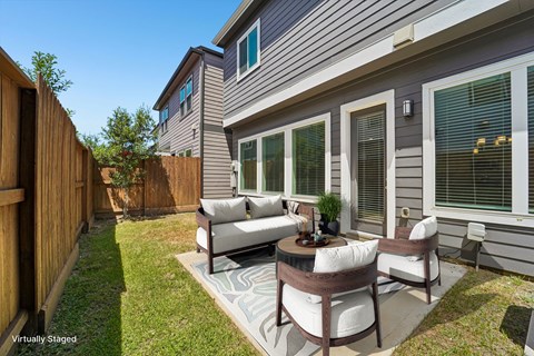 A patio with a table and chairs is in front of a house.