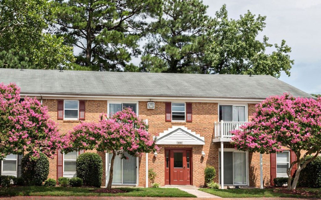a brick house with pink flowers in front of it