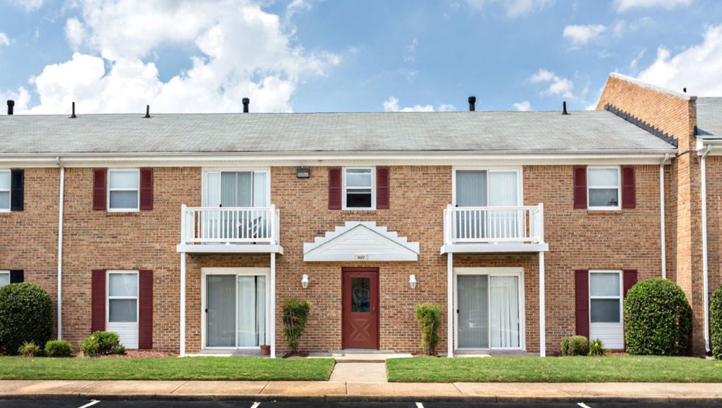 a brick house with a red door and a porch