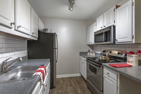 A kitchen with white cabinets and a black refrigerator.