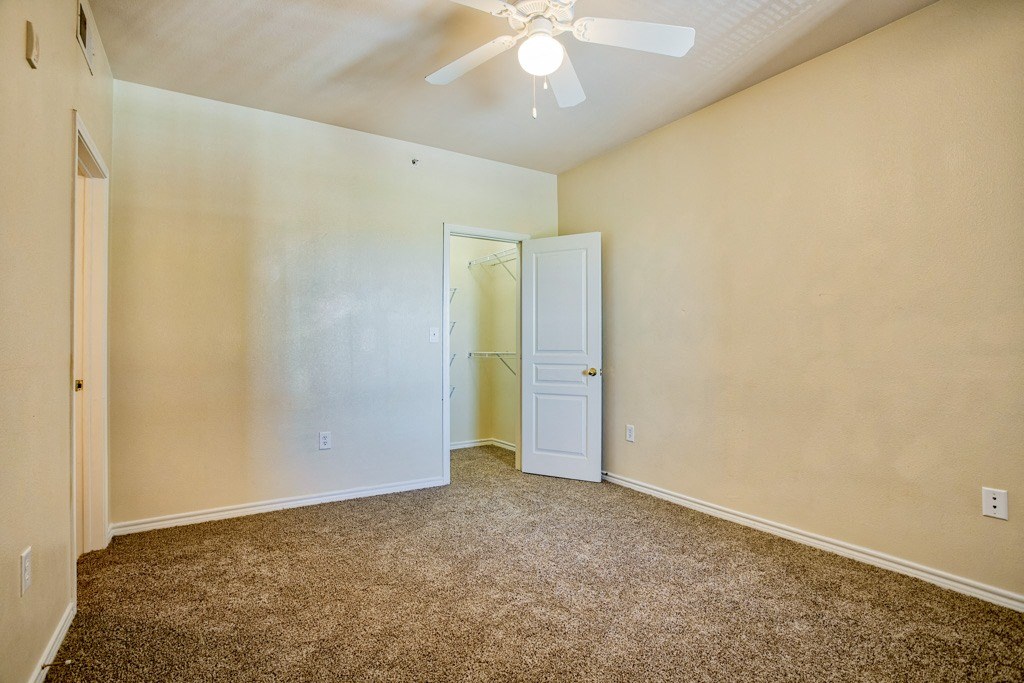 a bedroom with a ceiling fan and carpet floor
