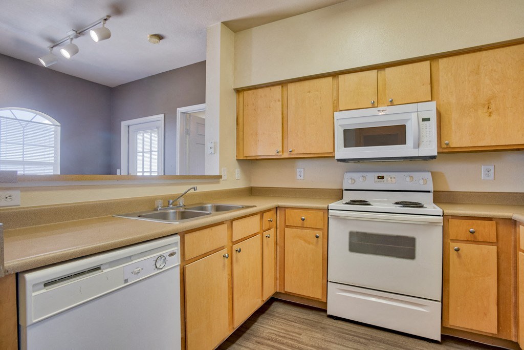 Kitchen with wood cabinets and wood floors and a stove with oven and microwave and dishwasher