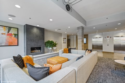 A modern living room with a grey sofa, a fireplace, and a painting on the wall.