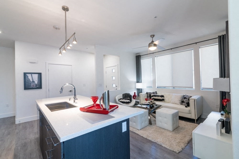 A kitchen with an island and ceiling light and fan and chairs and couch