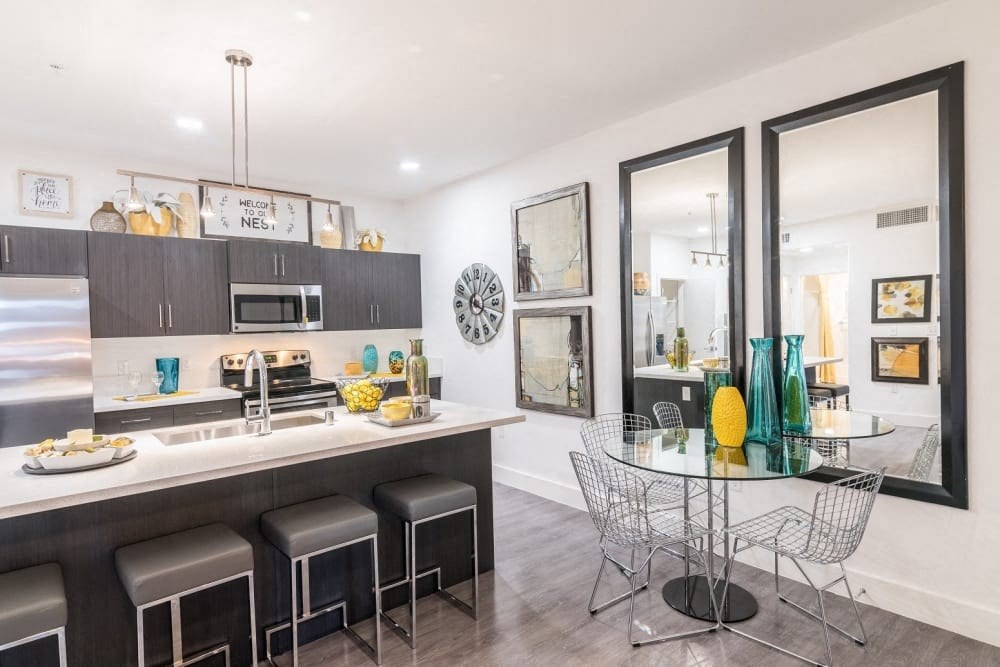 A kitchen with a dinning table and stools and ceiling light and island and oven and microwave and stove