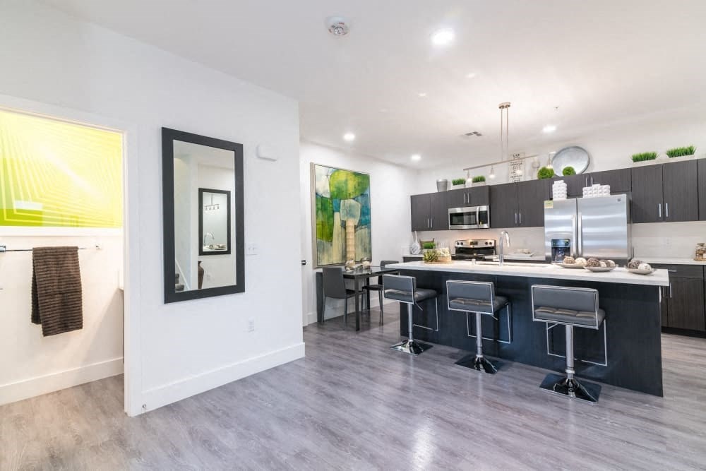 A kitchen with ceiling lights and bathroom and fridge and stools and island and microwave and oven and stove
