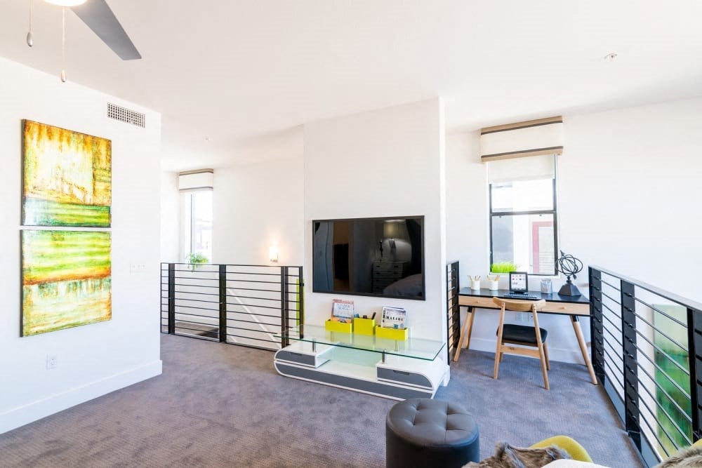 A living room with a tv and tv stand and desk and chair