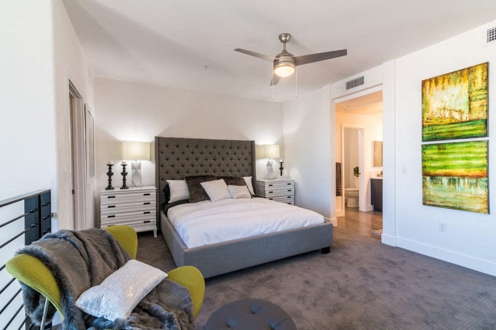 A bedroom with a bed and ceiling fan and bathroom