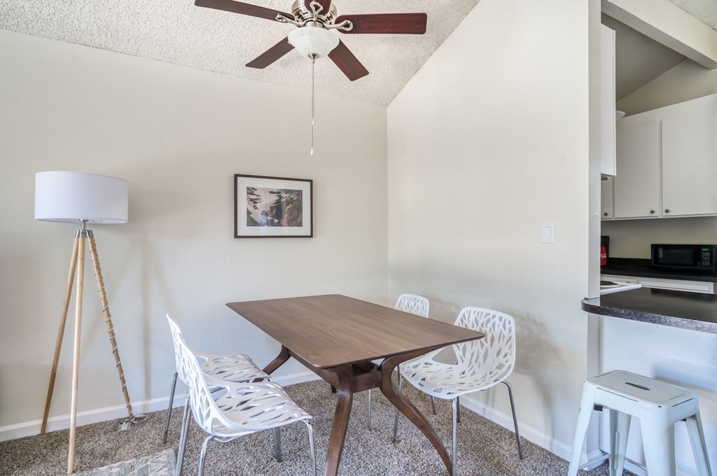a dining room with a wooden table and four white chairs