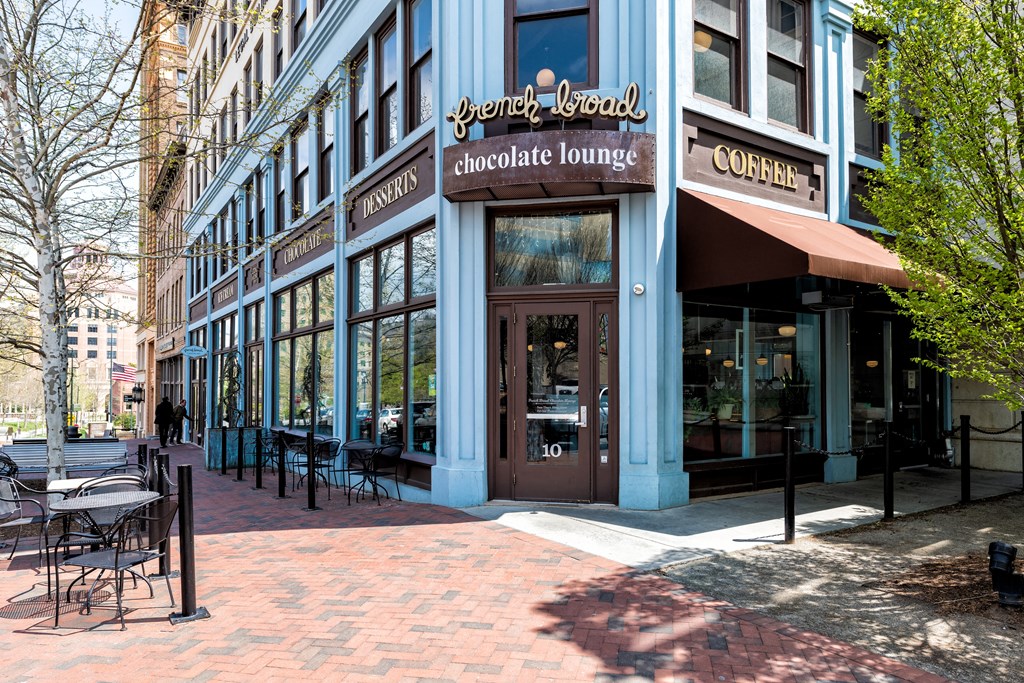 a street view of a blue building with tables and chairs outside