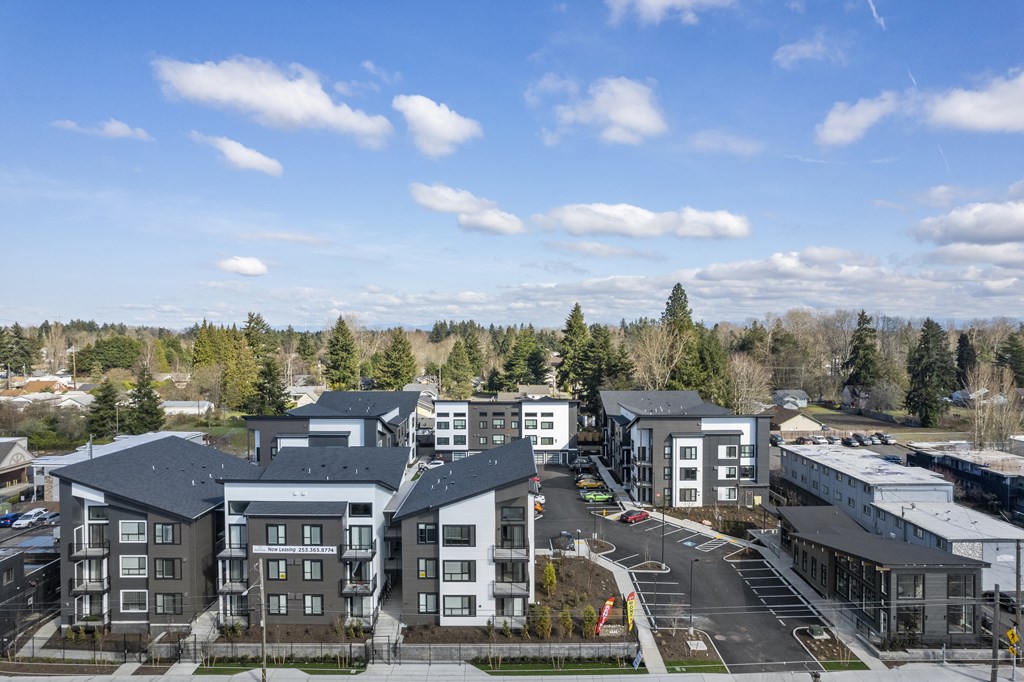 an aerial view of a row of apartment buildings with trees in the background,