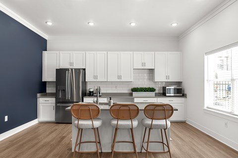 A kitchen with white cabinets and a stainless steel refrigerator.