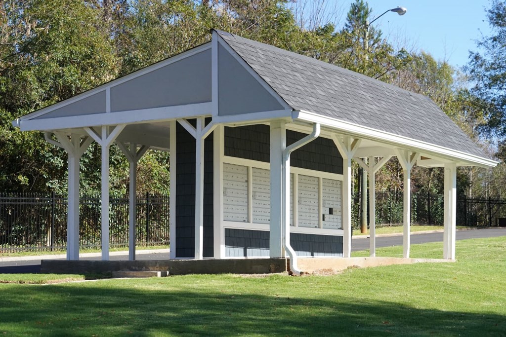 a kiosk in a park with a grassy area and trees in the background