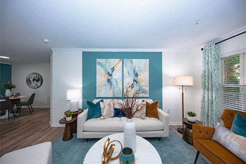 A living room with a white couch and a painting on the wall.