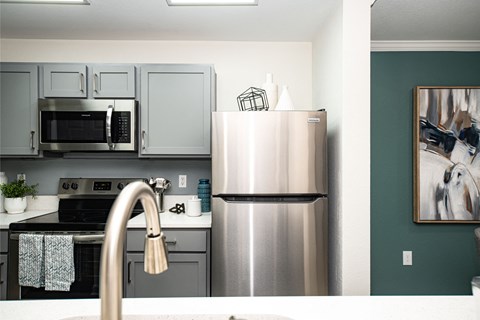 A modern kitchen with a stainless steel refrigerator and a white sink.