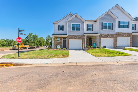 New townhomes for rent with white siding, brick accents, and attached garages.