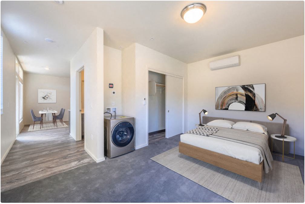 a bedroom with a bed and a washing machine in a room