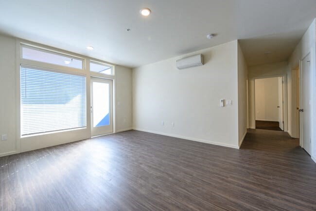an empty living room with hardwood floors and a large window