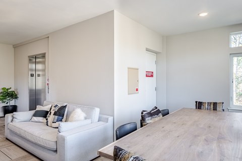 A white couch with pillows sits in a room with a wooden table at Emerald Crest, Bothell, WA 