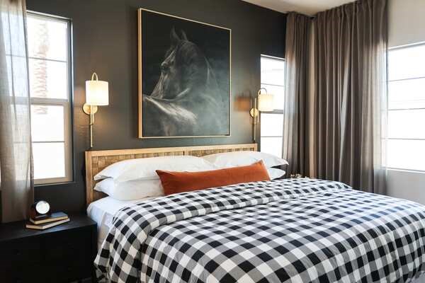 A bedroom with a black and white checkered bedspread and a painting of a horse on the wall.
