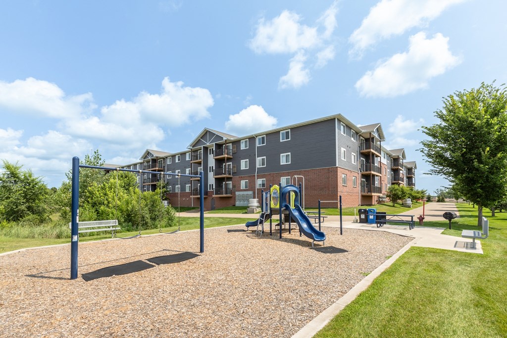 A playground with a slide and a bench in front of apartment buildings.