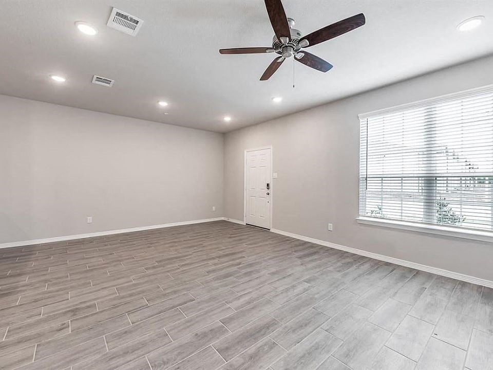 an empty living room with a ceiling fan and a window