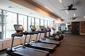 A gym with treadmors and a fan.