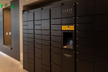 A row of black lockers with a yellow sign on the front of the closest one.