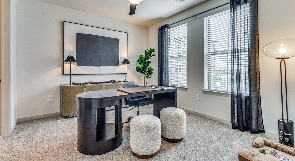 an office with a desk and chairs and a large window
