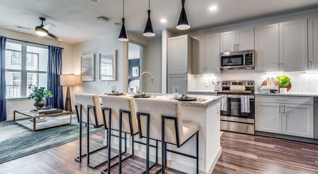 a kitchen with white cabinets and a bar with stools