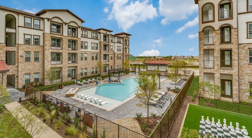 a resort style pool with lounge chairs in front of an apartment building