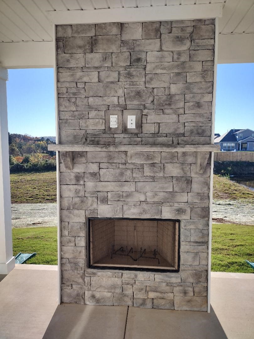 a stone fireplace on the porch of a house
