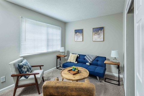 A living room with a blue couch and a wooden chair.