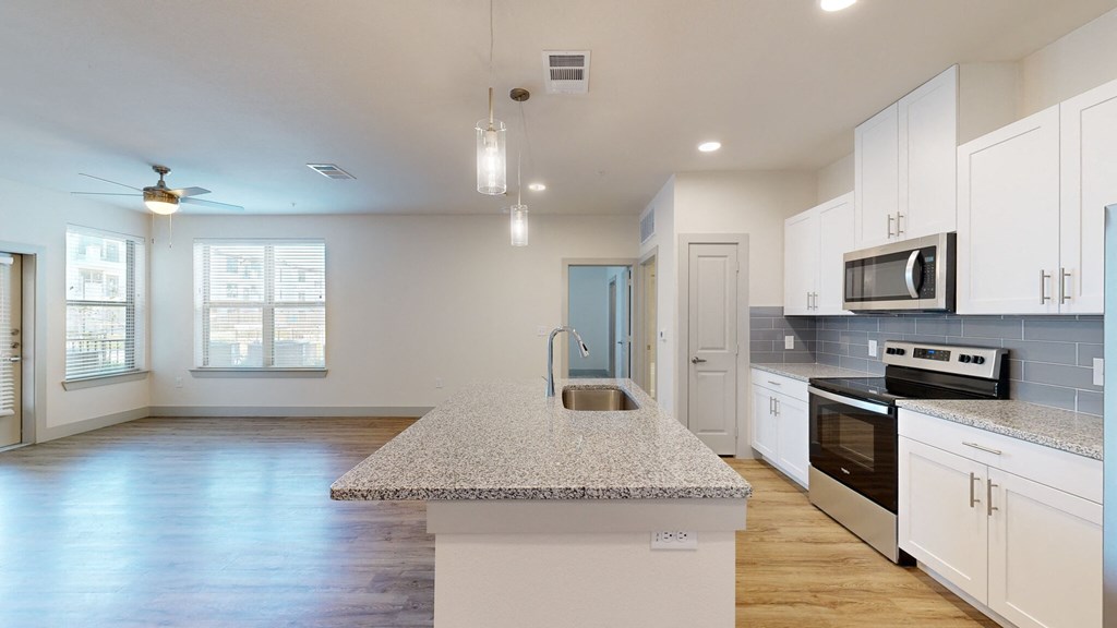 a kitchen with white cabinets and a granite counter top