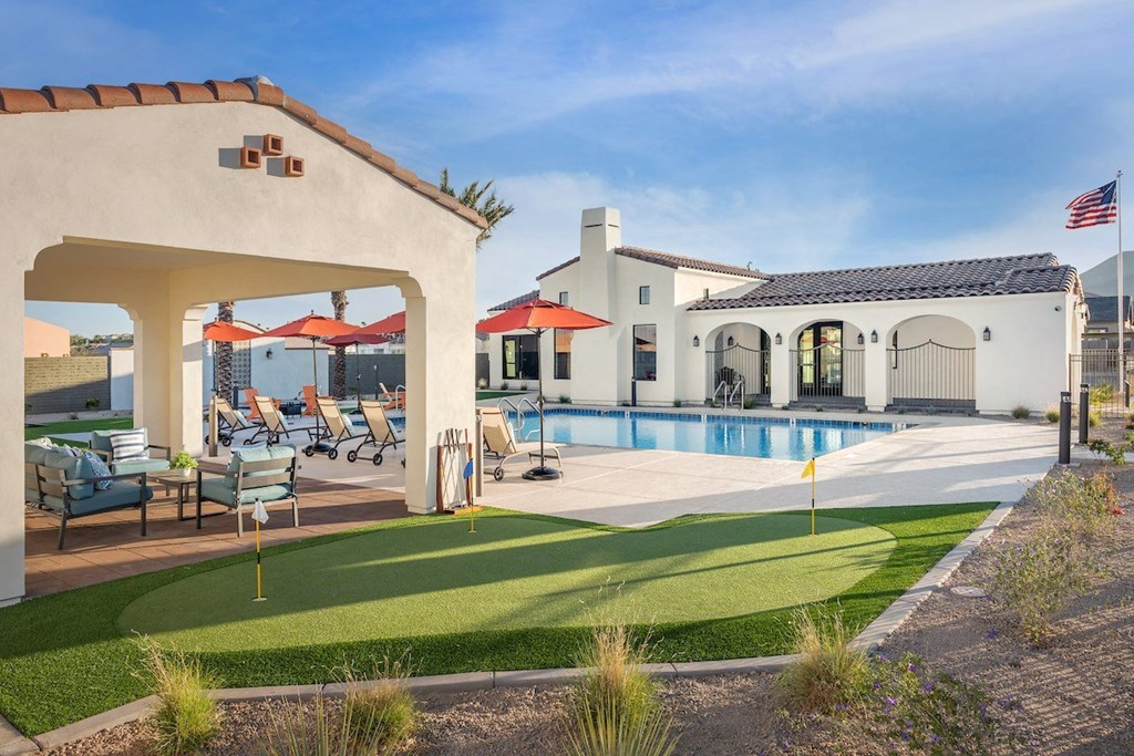 a backyard with a pool and a house with chairs and umbrellas