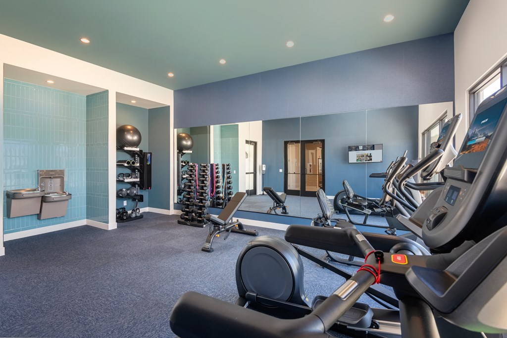 a gym with cardio equipment and weights in a building with blue walls
