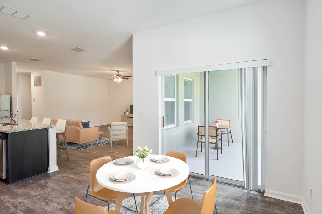 A dining room with a table set for two and chairs around it.